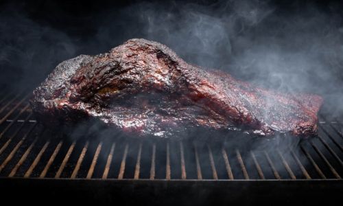 Smoke rising around a slow cooked beef brisket